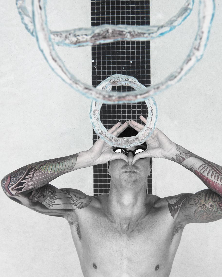 Anthony Ervin underwater with a ring-shaped bubble above him, photographed in black and white.