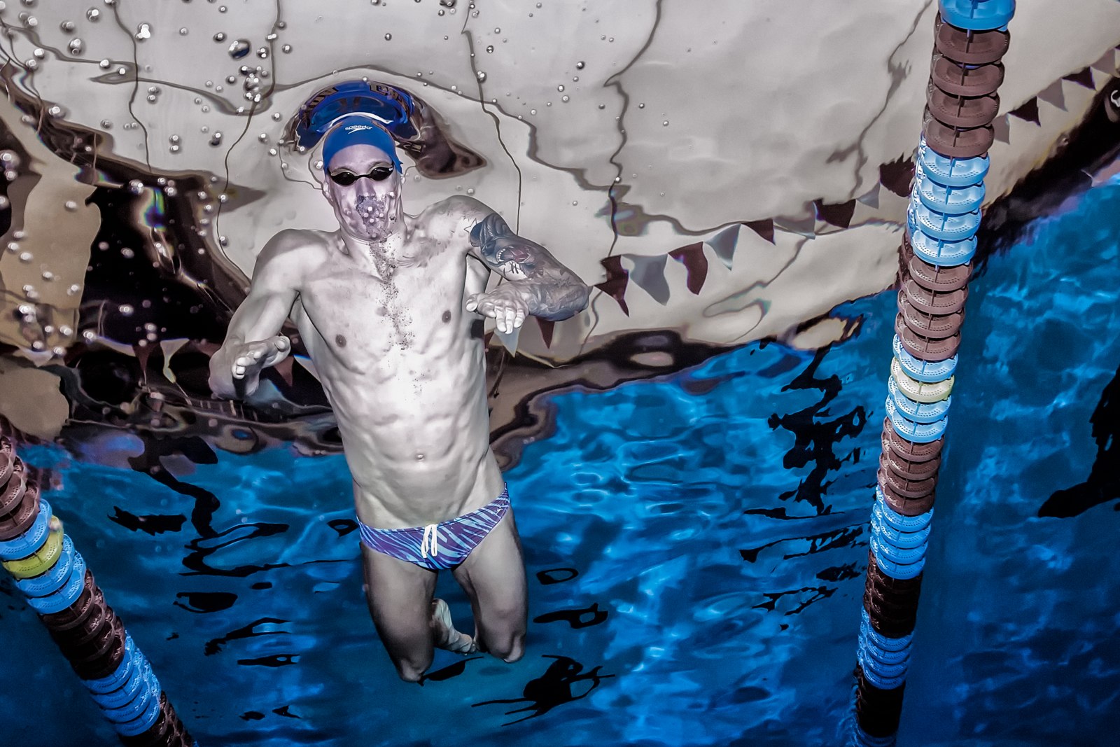 Caeleb Dressel beneath the surface, reflected in the water overhead.