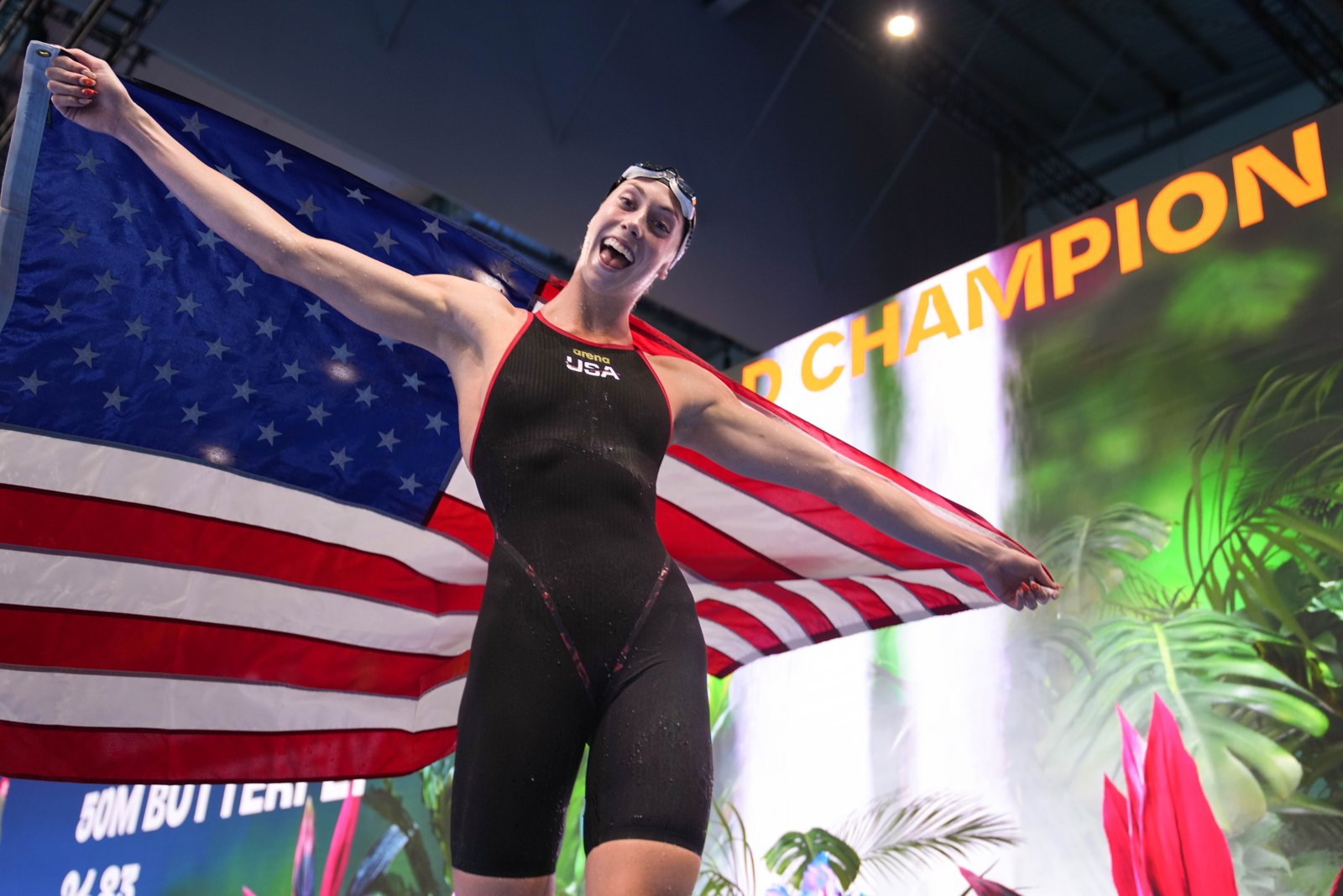 A swimmer celebrates with an American flag after a race.